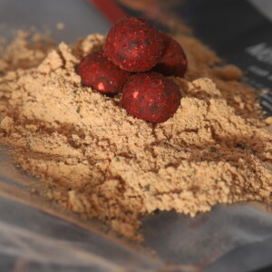 Hand-rolled Monster cork ball pop ups resting on a pile of Monster Red bird food boilie mix